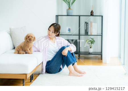 部屋でペットとくつろぐ若い女性 129415217