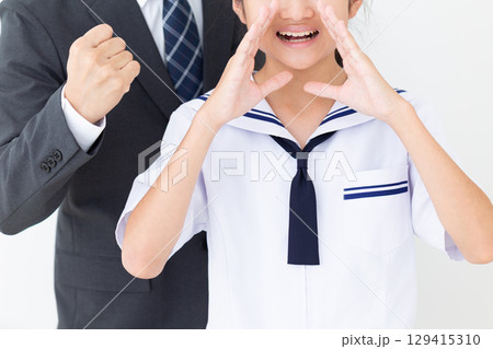 応援をする夏の学生服を着た中学生の女の子とスーツ姿のお父さん 129415310
