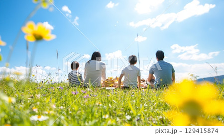 Family picnic in sunny meadow, back view, happiness 129415874