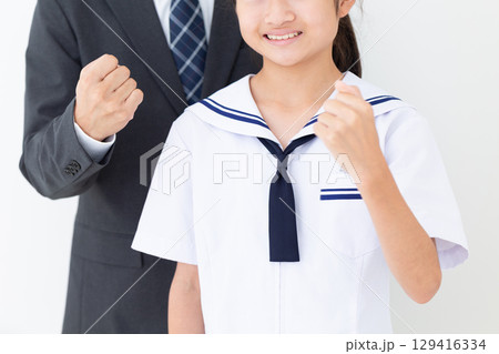 ガッツポーズをする夏の学生服を着た中学生の女の子とスーツ姿のお父さん 129416334