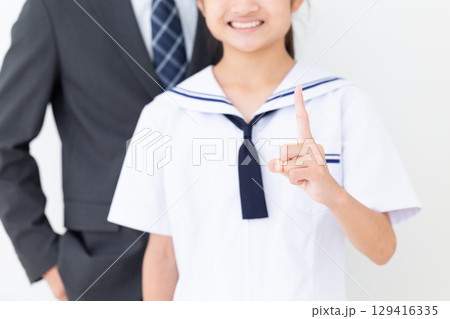 人差し指を立てる夏の学生服を着た中学生の女の子とスーツ姿のお父さん 129416335