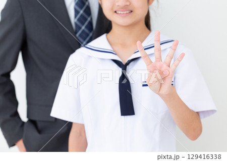 4本指を立てる夏の学生服を着た中学生の女の子とスーツ姿のお父さん 4本指を立てる夏の学生服を着た中学生の女の子とスーツ姿のお父さん 129416338