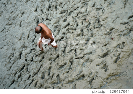 14th October 2023, Babughat, Kolkata, West Bengal, India. Elderly Man Walking Barefoot Through Muddy 14th October 2023, Babughat, Kolkata, West Bengal, India. Elderly Man Walking Barefoot Through Muddy 129417044