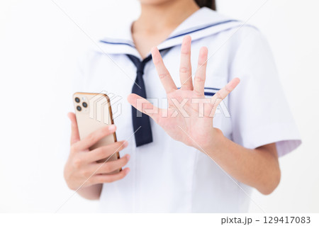 スマホを持って5本指を立てる夏の学生服姿の中学生女子 129417083