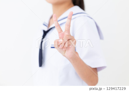 ピースサインをする夏の学生服姿の中学生女子 129417229