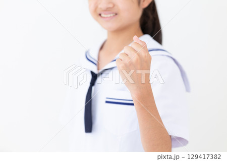 ガッツポーズをする夏の学生服姿の中学生女子 129417382