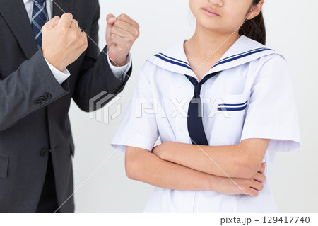 悩む夏の学生服を着た中学生の女の子と励ますスーツ姿のお父さん 129417740