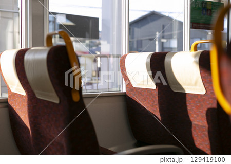 夕日が当たる電車の窓際座席 129419100