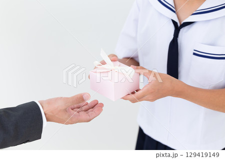 プレゼントを持つ夏の学生服姿の中学生女子 129419149