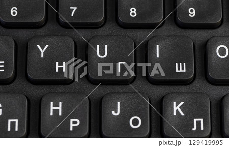 black new computer keyboard layout with Latin and Cyrillic alphabet, close up 129419995