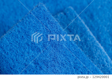 glued and tightly intertwined blue synthetic threads on a sponge that is used for cleaning and washing, close up 129420001