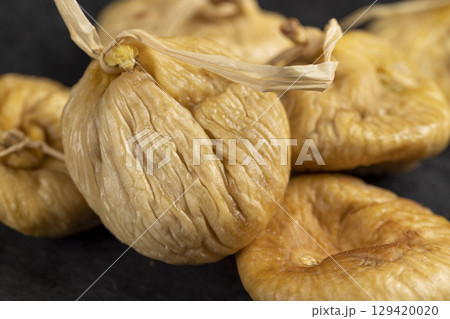 dried figs used in cooking close up, light figs naturally dehydrated in the sun on a black stone board 129420020