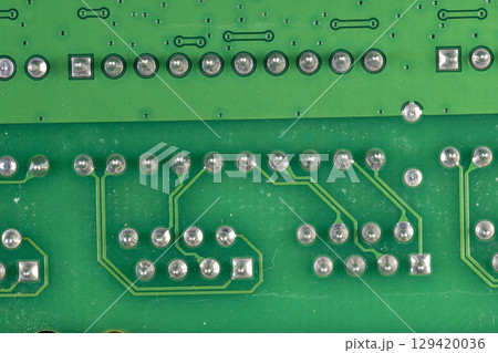 circuit board with a large number of contacts, a simple green printed circuit board with an electronic circuit with soldered elements circuit board with a large number of contacts, a simple green printed circuit board with an electronic circuit with soldered elements 129420036