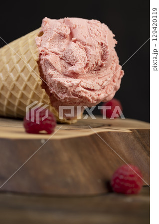 one ice cream lies on a walnut board close up, ripe red raspberries and raspberry cold natural ice cream on the table one ice cream lies on a walnut board close up, ripe red raspberries and raspberry cold natural ice cream on the table 129420119