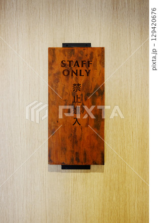 Close up wooden warning sign on wooden front door with message for staff only with Chinese character text below English words Close up wooden warning sign on wooden front door with message for staff only with Chinese character text below English words 129420676