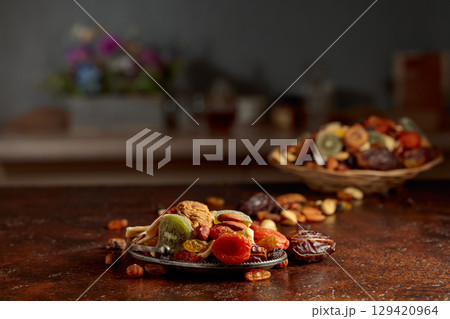 Dried tropical fruits, nuts, and raisins on a kitchen table. 129420964