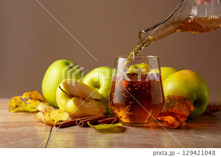 Apple juice is poured from a bottle into a glass. Apple juice is poured from a bottle into a glass. 129421048