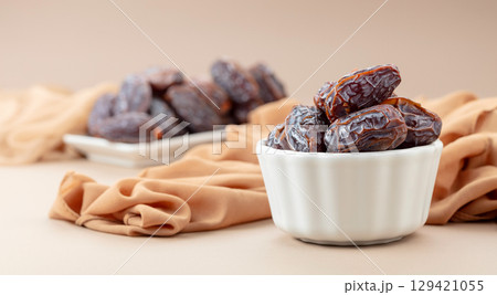 Dates in white dish on a beige background. 129421055