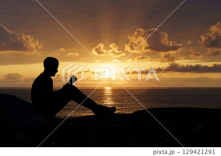Man Reading a Book at Sunset. Knowledge and Reflection 129421291