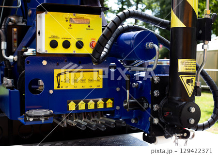 Close up of control panel and hydraulic system of manipulator used for cargo handling. The image highlights technical details and operational buttons essential for lifting and moving heavy loads Close up of control panel and hydraulic system of manipulator used for cargo handling. The image highlights technical details and operational buttons essential for lifting and moving heavy loads 129422371