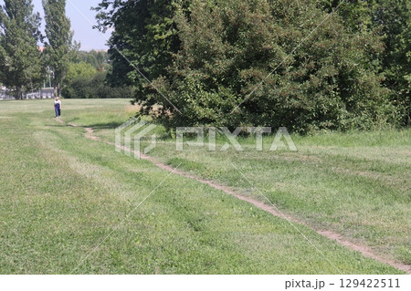 People walking on a trail in an open green field. 129422511