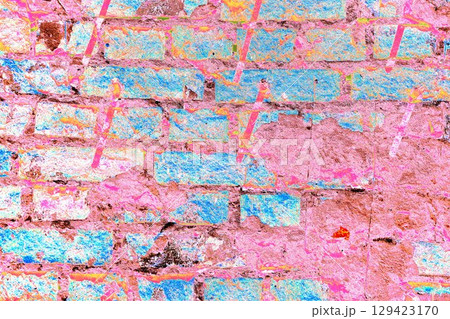 Peeling paint on a brick wall. Old brick wall with cracked peeling paint and metal pins. 129423170
