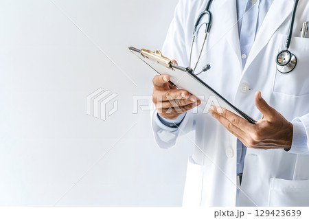Professional doctor with clipboard and stethoscope on white background, with copy space for medical info, health ads, or educational materials. 129423639