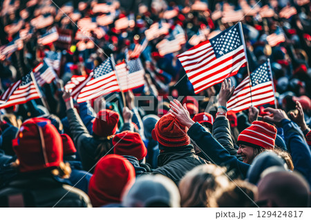 Crowd of people are holding up American flags in front of the Capitol building. 129424817