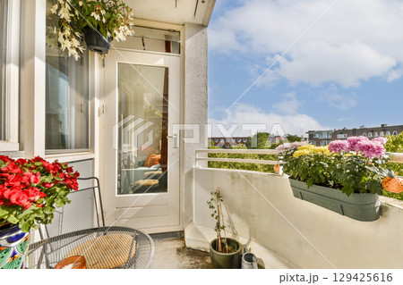 A bright balcony adorned with colorful flowers and greenery, offering a glimpse of a vibrant cityscape under a blue sky. A bright balcony adorned with colorful flowers and greenery, offering a glimpse of a vibrant cityscape under a blue sky. 129425616
