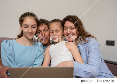 Family Laptop Togetherness: Parents and Daughters watch Laptop at Home, bonding indoor, enjoy together. Family Laptop Togetherness: Parents and Daughters watch Laptop at Home, bonding indoor, enjoy together. 129426216