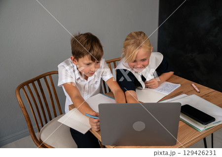 Children Laptop Classroom Learning: Two children studying together on a laptop at a desk in a classroom setting. 129426231