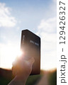 A Christian praying with the Holy Bible, the Word of Truth, against a backdrop of bright sunlight and a sunset. 129426327
