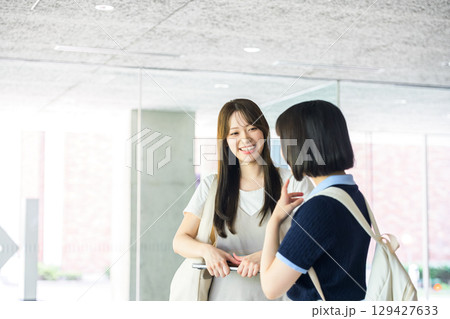 校内で会話を楽しむ女子大生二人 校内で会話を楽しむ女子大生二人 129427633