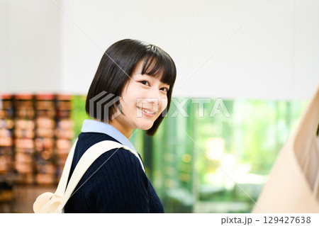 　図書館で振り向き笑顔の女子学生 129427638