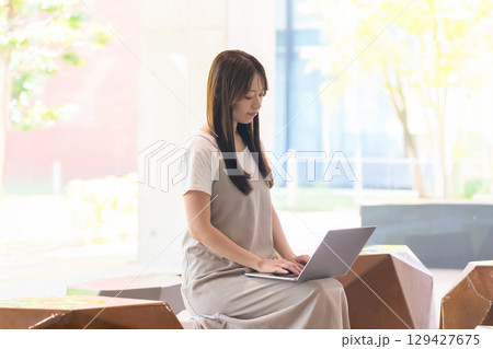　ノートパソコンで作業する女子学生 校内ベンチ 129427675