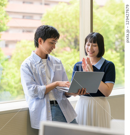 窓際で会話する大学生男女とノートPC 窓際で会話する大学生男女とノートPC 129427679