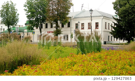 Beautiful yellow building and red, yellow and green wildflowers. Beautiful yellow building and red, yellow and green wildflowers. 129427863