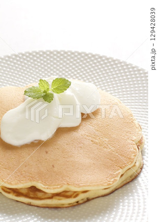 バナナとホイップクリームをトッピングしたパンケーキ 129428039