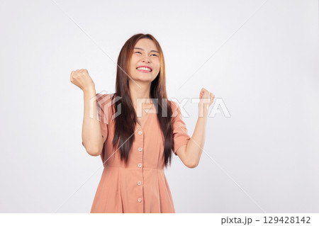 Success in her eyes and success in her pose the woman is excited smiling and raising fists expressing confidence isolated studio white background business profile style 129428142