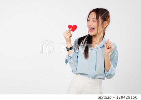 Cheerful asian woman holds red heart, full of love and emotion for valentine day, showing warm smile as lovely, attractive model holds a heart for valentine, headshot isolated studio white background Cheerful asian woman holds red heart, full of love and emotion for valentine day, showing warm smile as lovely, attractive model holds a heart for valentine, headshot isolated studio white background 129428150