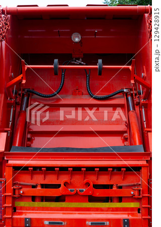 Close-up of the rear mechanism of a garbage truck designed to lift and empty waste containers. The hydraulic system with hooks and rollers is used for efficient trash collection and disposal Close-up of the rear mechanism of a garbage truck designed to lift and empty waste containers. The hydraulic system with hooks and rollers is used for efficient trash collection and disposal 129428915