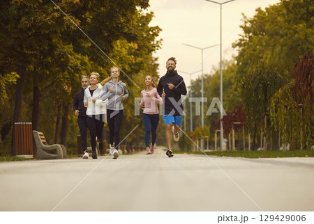 Happy young sport group of people jumping standing in a circle with hands up in nature. 129429006