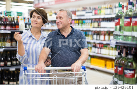 Mature couple husband and wife choose alcoholic drinks in supermarket 129429101