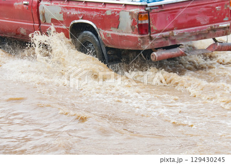 3. Close up of a car wheel driving through muddy red flood 3. Close up of a car wheel driving through muddy red flood 129430245