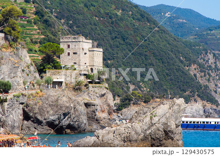 Torre Aurora - Down tower Castle in Monterosso al Mare. Mountain rock cliff in Ligurian sea. Coastline Torre Aurora - Down tower Castle in Monterosso al Mare. Mountain rock cliff in Ligurian sea. Coastline 129430575
