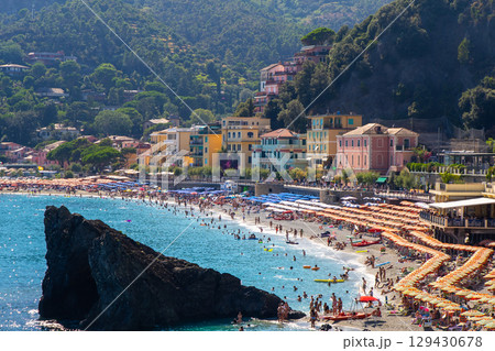 Umbrellas on the beach in summer. Italian holidays on the coast of the Ligurian blue Sea and Mountain rock. Liguria Monterosso. Umbrellas on the beach in summer. Italian holidays on the coast of the Ligurian blue Sea and Mountain rock. Liguria Monterosso. 129430678
