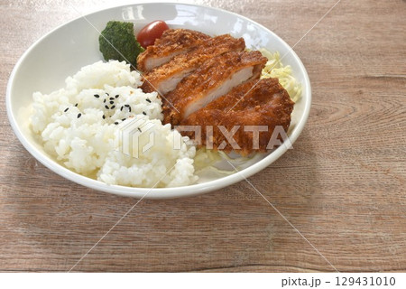 deep fried slice pork or tonkatsu with cabbage tomato and broccoli vegetable on black sesame rice in plate 129431010