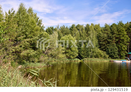 A small wooden house with boats by the riverbank 129431519