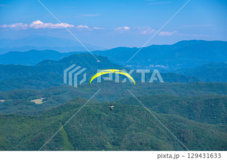 夏の空を飛ぶパラグライダー 129431633
