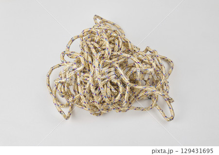 A tangled heap of rope lies on a plain white surface A tangled heap of rope lies on a plain white surface 129431695